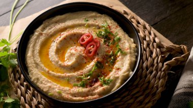 Seramik kasede nefis humus. Siyah ahşap arka planda renkli abur cubur kompozisyonu.