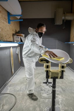 Sörf tahtası imalatı, sörf tahtası ayrıntıları üzerinde çalışan şekillendirici. Endüstriyel imalat, nitelikli profesyonel, mesleki ve istihdam kavramı.