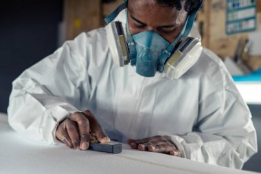 Sörf tahtası imalatı, sörf tahtası ayrıntıları üzerinde çalışan şekillendirici. Endüstriyel imalat, nitelikli profesyonel, mesleki ve istihdam kavramı.