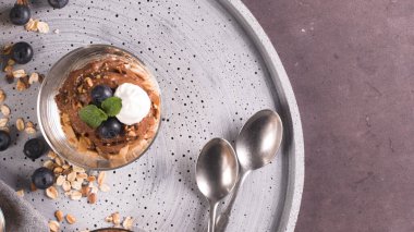 Cam bardak çikolata ve kestane mousse kavrulmuş badem ve yulaf ile dekore edilmiş ile siyah çilek ve nane yaprakları.