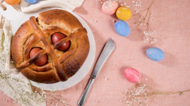 Masanın üstünde yumurta ve pembe masa örtüsü olan Paskalya folar..