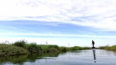 Bulutlu bir günde Portekiz 'deki Ria de Aveiro kanallarından birinde sörf tahtasıyla suyun üzerinde süzülüyor..