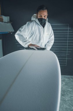 Sörf tahtası imalatı, sörf tahtası ayrıntıları üzerinde çalışan şekillendirici. Endüstriyel imalat, nitelikli profesyonel, mesleki ve istihdam kavramı.
