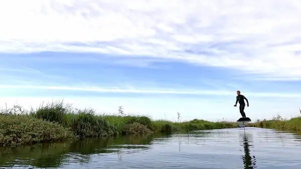 在多云的一天 滑翔机和他的滑翔板在葡萄牙阿韦罗街的一条运河里滑过水面 — 图库照片