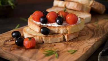 Krem peynirli taze bruschetta, siyah zeytin ve vişneli domates yakından..