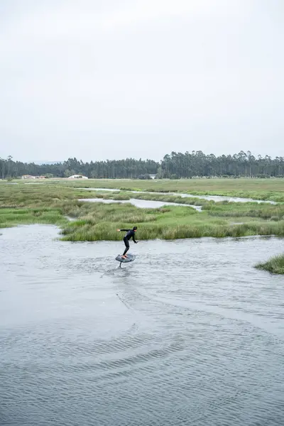 在多云的一天 滑翔机和他的滑翔板在葡萄牙阿韦罗街的一条运河里滑过水面 图库照片