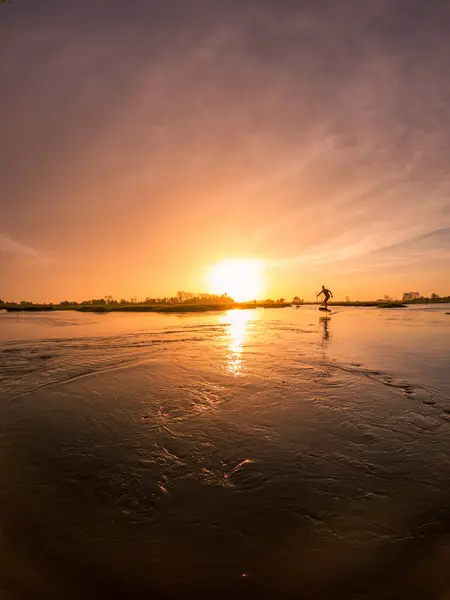 Tragflügelfahrer Gleitet Bei Sonnenuntergang Mit Seinem Board Über Das Wasser lizenzfreie Stockfotos