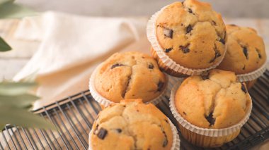 Chocolate chip muffins with milk served on glass cups on white kitchen countertop.
