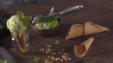 Koyu rustik bir kapta antep fıstığı dondurma ve kahverengi ahşap arka plan üzerinde waffle konisi.