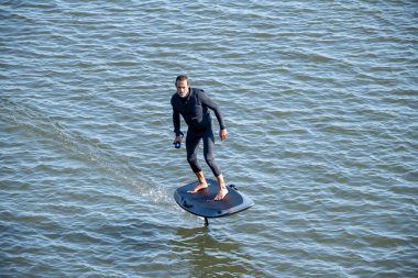 Sörf tahtasındaki siluetli adam su yüzeyinde süzülüyor..