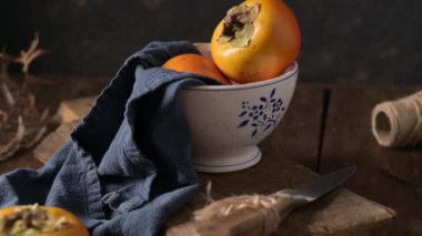 Kaba ahşap elementlerle donanma kumaşında yetişmiş hurma ağaçları hoş bir sonbahar manzarası yaratır. Yumuşak ışıklandırma meyvenin canlı rengini ve dokusunu vurgular.