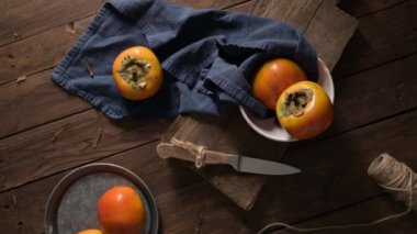 Kırsal bir ahşap masa üzerinde olgun hurmalar, mavi bir bez ve bir kesim tahtasıyla.