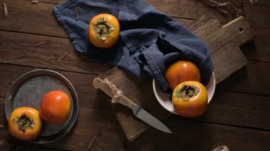 Kırsal bir ahşap masa üzerinde olgun hurmalar, mavi bir bez ve bir kesim tahtasıyla.