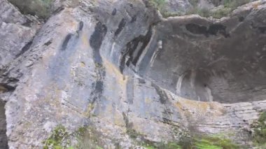 Buracas do Casmilo at Condeixa - Portekiz. Engebeli bir yamaçta yuva yapmış antik kireçtaşı mağaraları, bulutlu bir günde yeşil bitki örtüsü ve yosun kaplı kaya oluşumları arasında birden fazla doğal mağara açıkları barındırır..