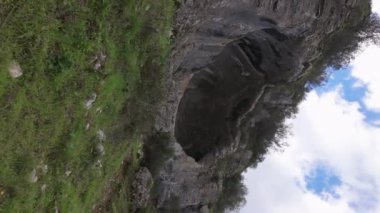 Buracas do Casmilo at Condeixa - Portekiz. Engebeli bir yamaçta yuva yapmış antik kireçtaşı mağaraları, bulutlu bir günde yeşil bitki örtüsü ve yosun kaplı kaya oluşumları arasında birden fazla doğal mağara açıkları barındırır..