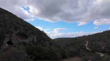 Buracas do Casmilo at Condeixa - Portekiz. Engebeli bir yamaçta yuva yapmış antik kireçtaşı mağaraları, bulutlu bir günde yeşil bitki örtüsü ve yosun kaplı kaya oluşumları arasında birden fazla doğal mağara açıkları barındırır..