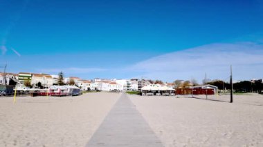 Figueira da Foz, Portekiz - 12 Kasım 2024: Figueira da Foz plajı, sahil barakaları, şehrin ufuk çizgisine doğru uzanıyor. Figueira da Foz uzun kumlu plajları ve canlı sahil atmosferiyle tanınır..