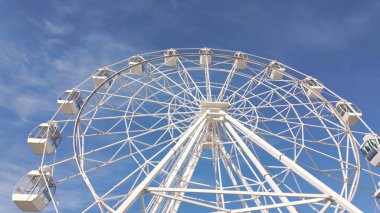 Açık mavi gökyüzüne karşı büyük beyaz bir dönme dolap..