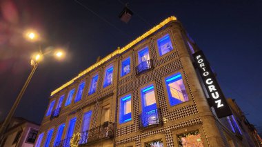 Gaia, Portekiz - 28 Kasım 2024: Portekiz 'in Gaia kentindeki ikonik Porto Cruz binası, mavi ışıkla aydınlatılmış, bölgenin zengin şarap üretim mirasının bir sembolü olan gece gökyüzüne karşı görkemli bir şekilde ayakta duruyor..