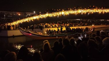 Aveiro, Portugal - December 1, 2024: Santa Claus arrival in Aveiro, Portugal, with a boat parade under a bridge adorned with festive lights, drawing a large crowd clipart