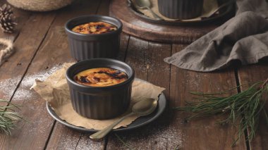 Creme brulee. Üzerinde karamelli şeker, kaşıklar, koyu kırsal masa olan Fransız vanilyalı tatlı kaseleri..