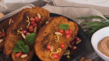 Traditional Christmas Rabanadas with pommegranate seeds, pine nuts and cinnamon. Spanish Torrijas or french toasts close up on the countertop.