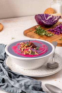 Mor lahana çorbası, fındıklı ve biberiyeli, mor lahanalı ve arka plandaki ahşap tahtada taze biberiyeli.