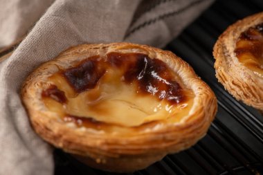 Yumuşak, katmanlı ve karamelli hamur işleri serinletici bir askıda dinleniyor, kısmen bej bir bezle kaplanmış, lezzetli dokularını sergiliyorlar.