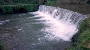 Cascata do Outeiro yakınlarında insan yapımı bir Weir üzerinde güçlü bir su akışı var. Sahne, Oliveira de Azemis 'teki doğa ve insan etkisinin dinamik etkileşimini gösteriyor..