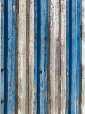 Yıpranmış mavi ve beyaz boyanmış ahşap tahtalar desenli bir duvar oluşturur..