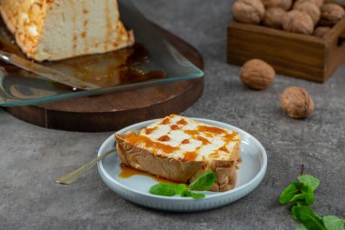 Nefis bir molotof dilimi, şekerli ve taze nane yapraklarıyla süslenmiş geleneksel karamelize edilmiş yumurta akı pudingi, açık mavi bir tabakta duruyor.