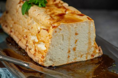 Cazip bir yakın plan çekimde bir dilim molotof, geleneksel karamelli yumurta akı pudingi bol bol tatlı şurup serpiştirilmiş ve taze yeşil nane yapraklarıyla süslenmiş.