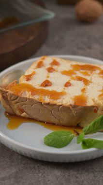 Tatlı karamel serpiştirilmiş ve taze nane ile süslenmiş, küçük yuvarlak bir tabakta sunulan karamelli molotof pudinginin çekici, bireysel bir porsiyonu..