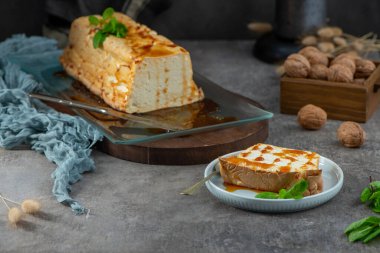 Bir dilim molotof, şekerli ve naneli geleneksel karamelize edilmiş yumurta akı pudingi, yakınlardaki pudingin geri kalanıyla birlikte bir tabakta.