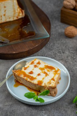 Kısmen yenmiş bir molotof dilimi, geleneksel karamelleştirilmiş yumurta akı pudingi, tatlı şurubu serpiştirilmiş ve nane ile süslenmiş, açık mavi bir tabakta bir kaşıkla oturuyor.