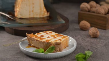 Çekici bir dilim karamelli molotof pudingi, tatlı karamel serpiştirilmiş ve taze nane ile süslenmiş, küçük beyaz bir tabakta altın bir kaşıkla sunuluyor..