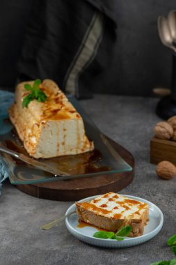 Bir dilim molotof, şekerli ve naneli geleneksel karamelize edilmiş yumurta akı pudingi, yakınlardaki pudingin geri kalanıyla birlikte bir tabakta.