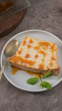 Tek bir dilim karamelli molotof pudingi, zengin karamel sosuyla süslenmiş ve taze nane yapraklarıyla süslenmiş, Yuvarlak bir kaşıkla sunulmuş, doğrudan yukarıdan bakıldığında.