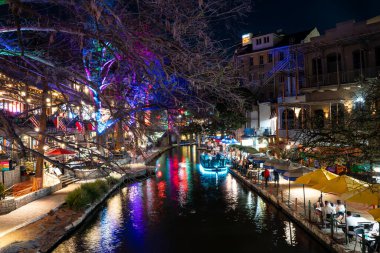 San Antonio, Teksas - 20 Şubat 2024 San Antonio Teksas 'taki tarihi sahil yürüyüşünün gece manzarası akşam saatlerinde renkli ışıklar ve kanallarla görüldü