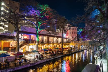 San Antonio, Teksas - 20 Şubat 2024 San Antonio Teksas 'taki tarihi sahil yürüyüşünün gece manzarası akşam saatlerinde renkli ışıklar ve kanallarla görüldü