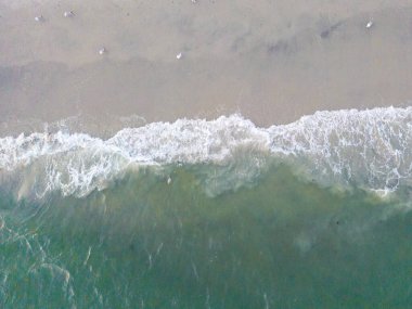 Seashore coastal ocean and beach sand seen from overhead view with tide and waves 