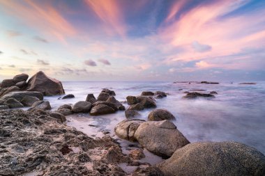 Aruba sahili boyunca kayalıklar, kayalar ve gün batımıyla birlikte kayalık bir sahil şeridi.
