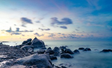 Aruba sahili boyunca kayalıklar, kayalar ve gün batımıyla birlikte kayalık bir sahil şeridi.
