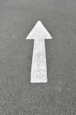 İleriye giden yolu gösteren ve asfalt yolda yönü gösteren beyaz boyanmış ok..