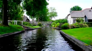 Turistler Hollanda 'nın Giethoorn kasabasındaki bir kanalda tekne turunun keyfini çıkarıyorlar..