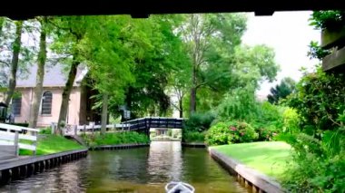 Turistler Hollanda 'nın Giethoorn kasabasındaki bir kanalda tekne turunun keyfini çıkarıyorlar..