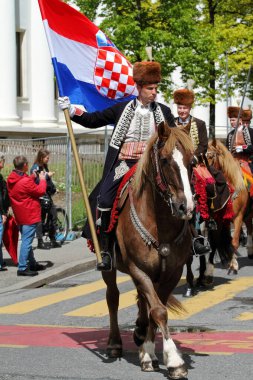 GENEVA; SWITZERLAND-May 04, 2024: Standard Bearer leads Sinjska Alka Croatia Cavalry squad - street parade participants. Old Grenadiers March, 275-years anniversary of the Vieux Grenadiers society, May 04, 2024 clipart