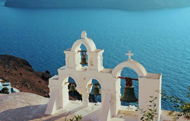 Mavi denizin arka planında eski bir Hıristiyan kilisesi çanları olan antik çan kulesi. Santorini Adası 'ndan Caldera. Yunanistan.