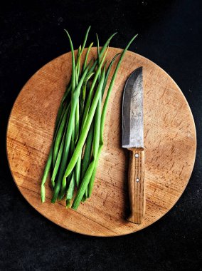 Kesme tahtasında taze soğan ve mutfak bıçağı.