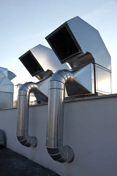 Metal industrial exhaust systems on the roof of the building.
